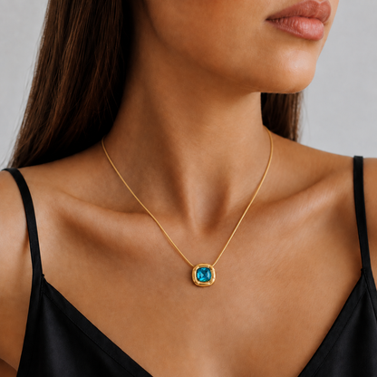 Paloma Cushion Stone Necklace – blue pendant in a gold setting worn with a black top