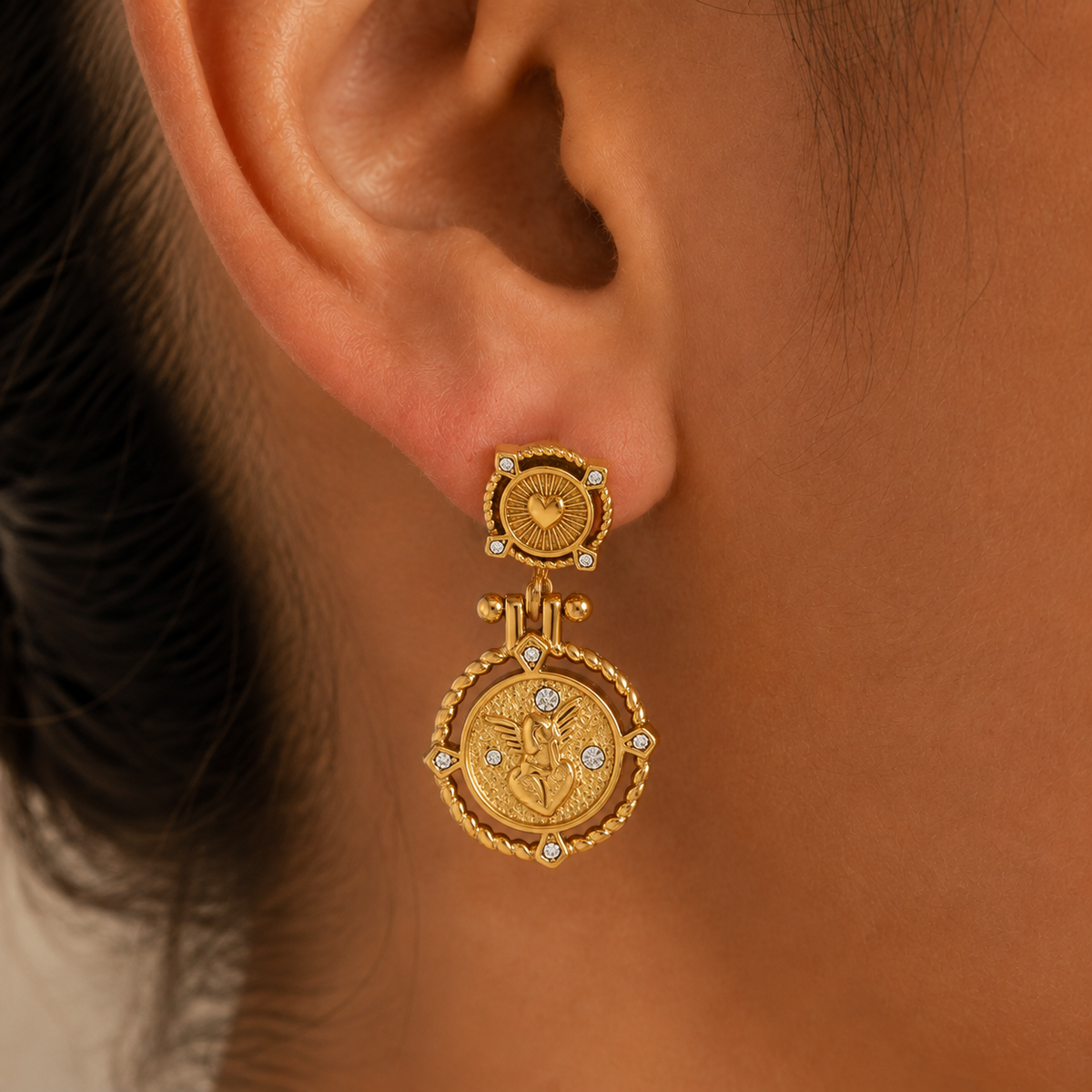 Seraphine Charm Earrings – gold heart and angel medallion drop earring worn on an ear