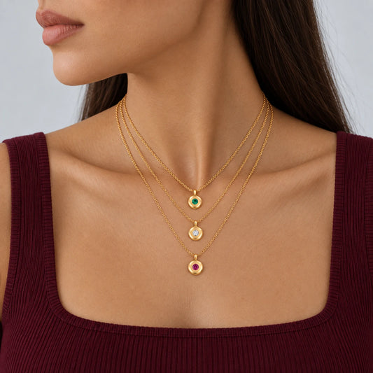 Model wearing three layered Ruth Birthstone Necklaces with green, clear and pink stones and a burgundy top